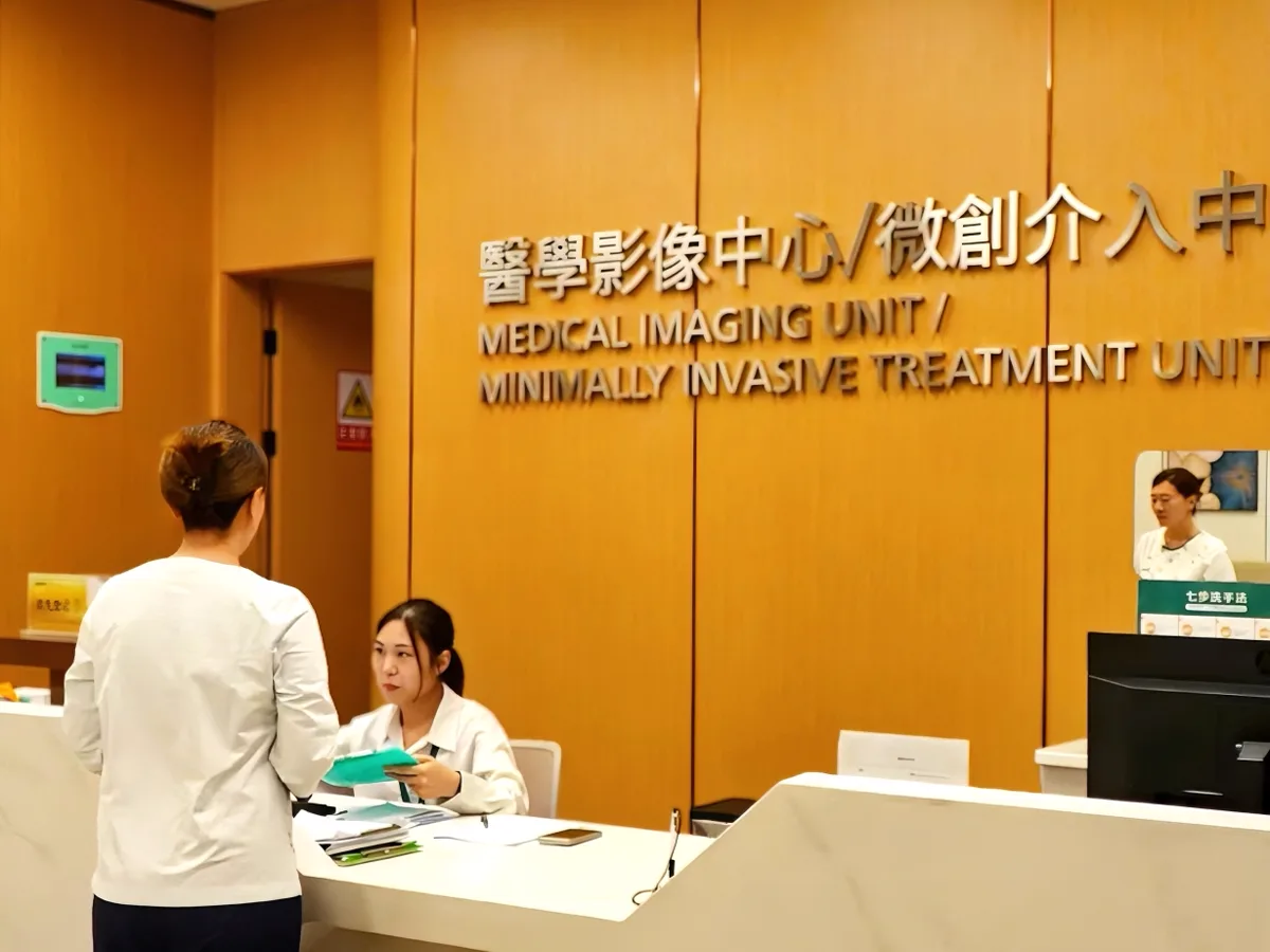 A visitor speaking with a staff member at a medical department desk